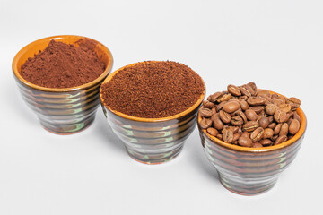 three small saucers with coffee beans, ground coffee and cocoa on a white background.