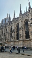 Milan Italy- October 17, 2022: Milan cathedral Duomo di Milano with gothic spires and white marble statues. Top tourist attraction on piazza in Milan, wide angle view of old gothic architecture.