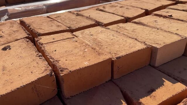 Slow motion video with pallets of solid red bricks at a construction site.