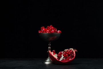 Pomegranate on a black background. Peeled pomegranate seeds