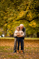 Fototapeta premium Grandfather spending time with his granddaughter in park on autumn day