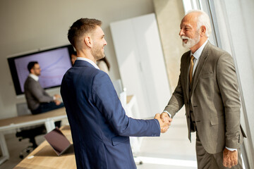 Senior business man handshaking with his young colleague