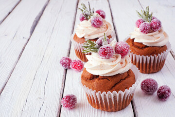 Christmas gingerbread cupcakes with frosty cranberries. Close up on a rustic white wood table background.