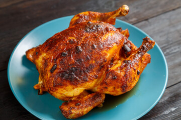 Whole baked chicken carcass in soy sauce with a crispy crust on a blue plate.