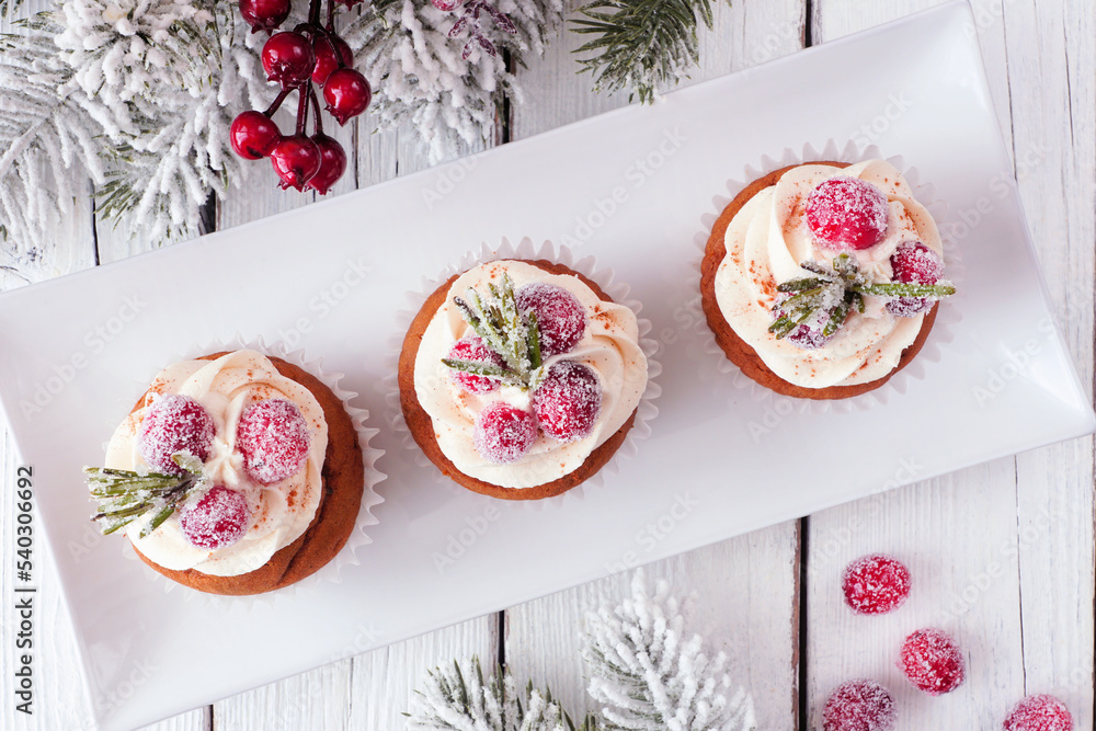 Poster christmas gingerbread cupcakes with frosty cranberries. top down on a white wood table background wi