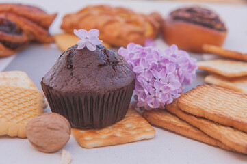 Chocolate muffin and assorted pastries with lilac flowers