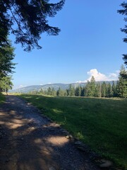 Summer day blue sky mountains landscape. Nature landscape with sun and blue sky. Summer travel in Europe mountains. Nature, lake, forest, trees hiking path. Clouds on blue sky. Forest landscape hiking