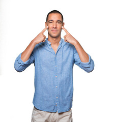 Fototapeta premium Hesitant young man making a gesture of being careful with his hand pointing at his eye