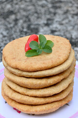 closeup the bunch brown color frayed tortilla with red chilly and green mint in the plastic plate on the soft focus natural brown background.