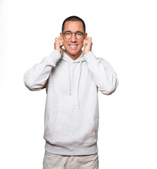 Fototapeta premium Young man worried about loud noises and covering his ears