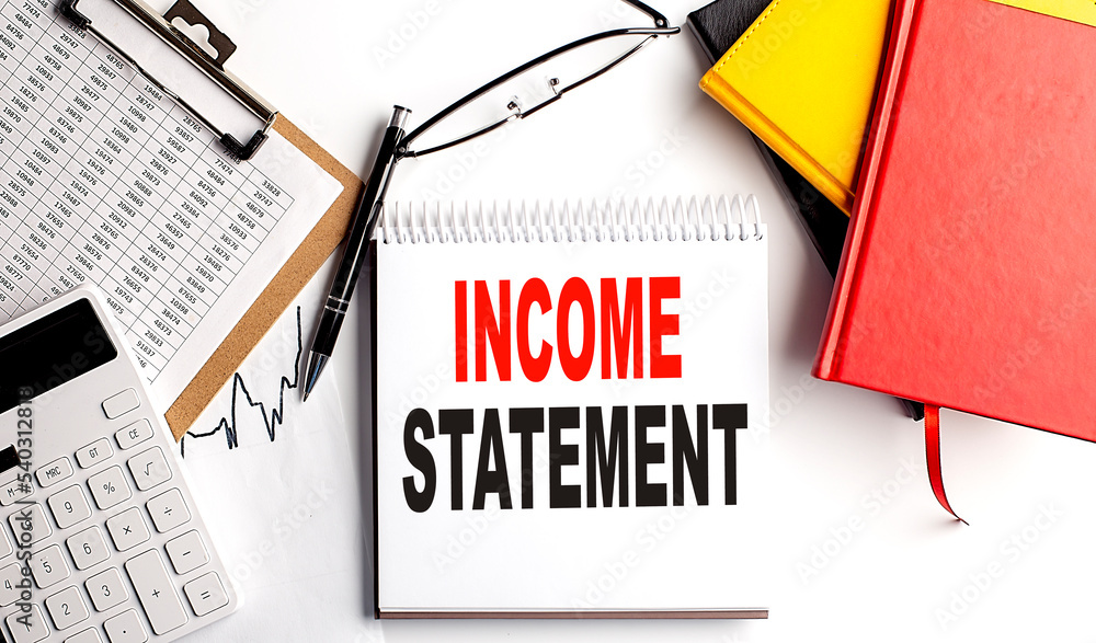 Aufkleber income statement text on notebook with clipboard and calculator on white background