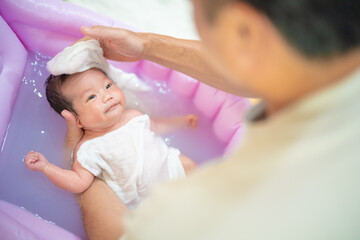 Obraz na płótnie Canvas 沐浴で頭を洗われて笑顔の赤ちゃん（新生児・パパ・父・子供・子ども・0歳・育児・子育て・お風呂・入浴）