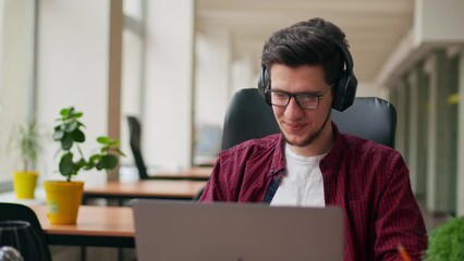 Developer, video editor man in headphones working with laptop at spacious coworking alone enjoying music. Stylish creative musician producer listens song in office alone. Online gamer playing games. - Powered by Adobe