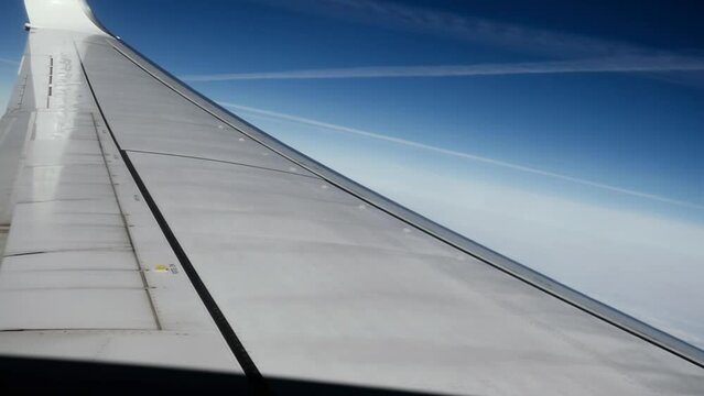 View through the aircraft airplane window at clear blue sky and trails from other planes