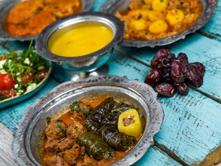 Eid Mubarak Traditional Ramadan Iftar dinner. Assorted tasty food in authentic rustic dishes on wooden blue background. Turkish Bosnian food meat kebab, pita, Sarma, klepe, sogan dolma.