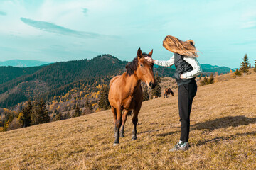 Cute girl with her horse in a beautiful meadow illuminated by warm evening light