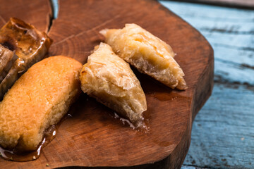 Ramadan Kareem, traditional Turkish middle eastern Iftar sweets Baklava with pistachios and fresh honey on rustic wooden plate and vintage blue background table. Top view.