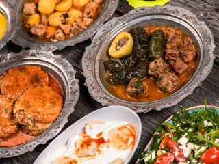 Eid Mubarak Traditional Ramadan Iftar dinner. Assorted tasty food in authentic rustic dishes on wooden blue background. Turkish Bosnian food meat kebab, pita, Sarma, klepe, sogan dolma.