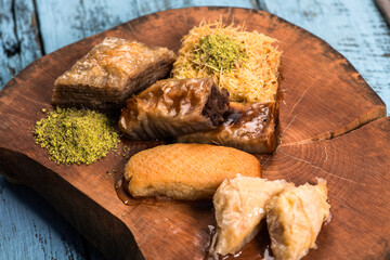 Ramadan Kareem, traditional Turkish middle eastern Iftar sweets Baklava with pistachios and fresh honey on rustic wooden plate and vintage blue background table. Top view.