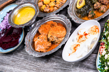 Eid Mubarak Traditional Ramadan Iftar dinner. Assorted tasty food in authentic rustic dishes on wooden blue background. Turkish Bosnian food meat kebab, pita, Sarma, klepe, sogan dolma.