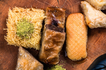 Ramadan Kareem, traditional Turkish middle eastern Iftar sweets Baklava with pistachios and fresh honey on rustic wooden plate and vintage blue background table. Top view.
