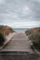 Vertical shot of a wooden path leading up to a beach in Germany on a cloudy day