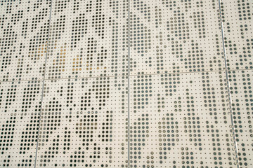 Beige sheet metal wall with holes in a close-up view