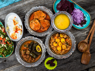 Eid Mubarak Traditional Ramadan Iftar dinner. Assorted tasty food in authentic rustic dishes on wooden blue background. Turkish Bosnian food meat kebab, pita, Sarma, klepe, sogan dolma.