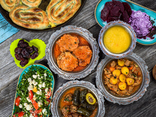 Eid Mubarak Traditional Ramadan Iftar dinner. Assorted tasty food in authentic rustic dishes on wooden blue background. Turkish Bosnian food meat kebab, pita, Sarma, klepe, sogan dolma.