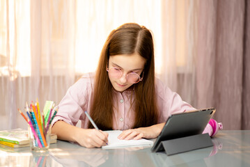 A teenage girl learns online from home. Education.