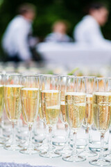 Stylish champagne glasses and food appetizers on table at wedding reception