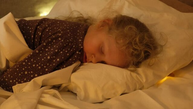 tooth fairy coin under pillow, milk tooth reward, cute cheerful girl sleeping on her bed, light under pillow