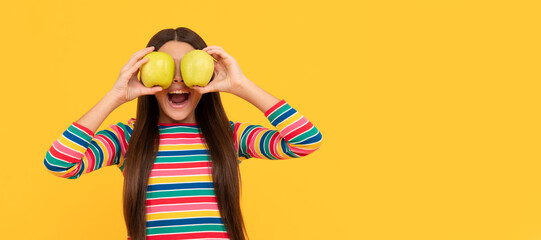 Happy girl child have fun holding apple fruit at eyes yellow background, eye health. Child girl...