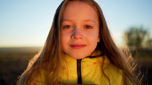 Close-up portrait of cute fair-haired girl. child looks into camera lens. One baby girl with blond hair looks forward into camera. Cute little girl face closeup