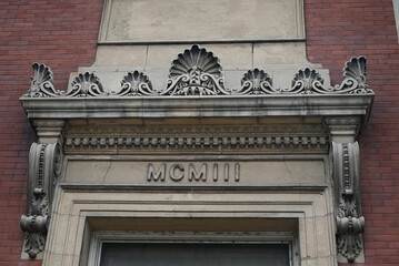 Closeup of a beautifully detailed entrance of a building with roman numerals MCMIII meaning 1903