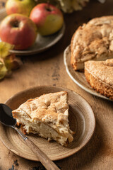 Piece of apple pie charlotte with apples and flowers on wooden background