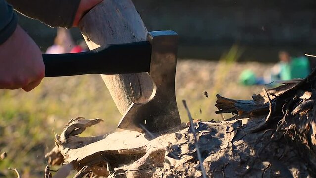 a boy chops wood with an ax
