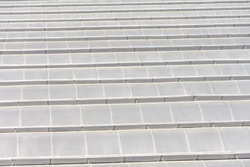 Roofs of greenhouses made of polypropylene plastic built in a row, aerial view.