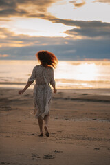 curly girl at sunset runs on the beach