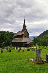 Fototapeta na wymiar Kaupanger stave church, Sogndal, Norway - Old wooden church with cemetery and green meadow.