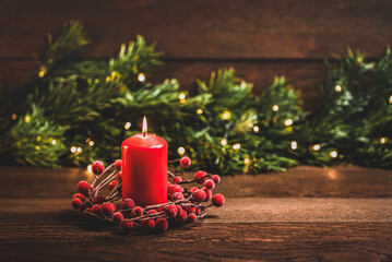 Merry Christmas and Happy New Year! Red candle, a wreath of red berries and fir branches on a...