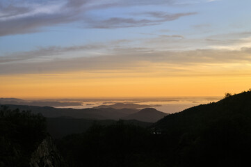Fototapeta premium Sunset, irradiated orange clouds over the sea and mountains in Preikestolen park, Norway