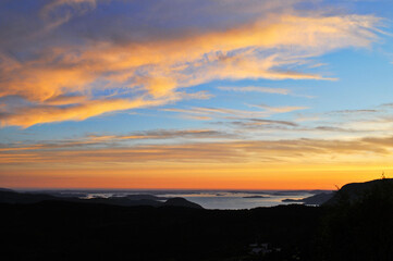Sunset, irradiated orange clouds over the sea and mountains in Preikestolen park, Norway