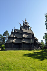 Fototapeta na wymiar Oslo, Norway - Old memorial wooden church on Bygdoy peninsula and green meadow