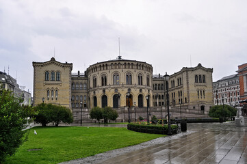 Oslo, Norway - The old parliament building in the city center. Wet sidewalk from rain with park.