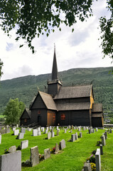 Fototapeta na wymiar Lom, Norway - old wooden church with cemetery. Stone tombstones.