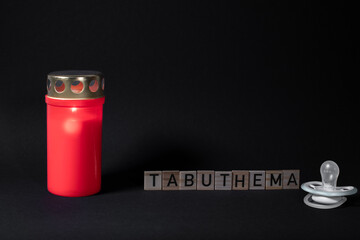 Buchstaben mit dem Wort Tabuthema mit Kerze und Schnuller auf schwarzen Hintergrund mit Platz für...