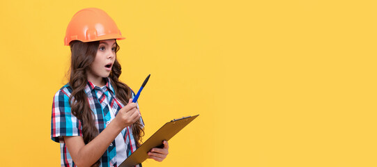 safety work expertise. amazed girl in protective hard hat making notes. Child builder in helmet horizontal poster design. Banner header, copy space.