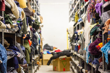 Humanitarian aid station, interior of industrial warehouse with used clothes for the poor,...