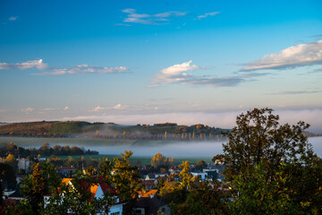 a large valley with a city and incoming fog